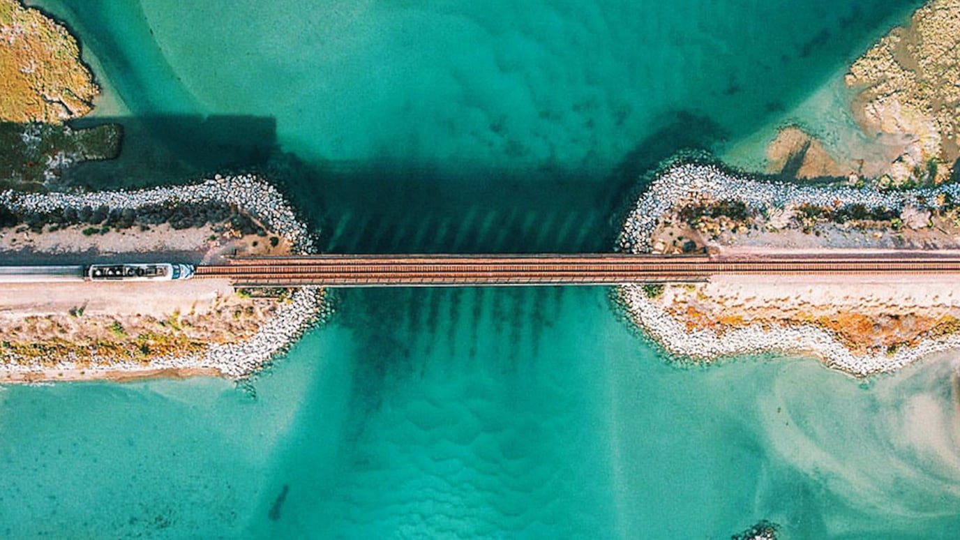 Overhead photogrpah of train crossing bridge body of water