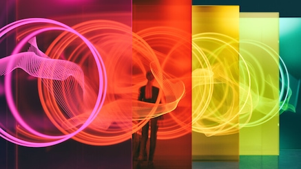 A person standing among glass walls illuminated by glowing rings