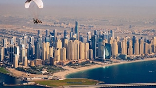 Photograph of microlite flying towards city with skyscrapers