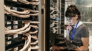 Network engineer using laptop to test server rack installation