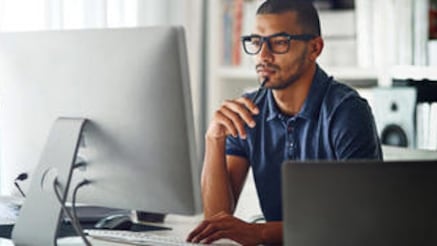 Man facing working at desk, looking at monitor