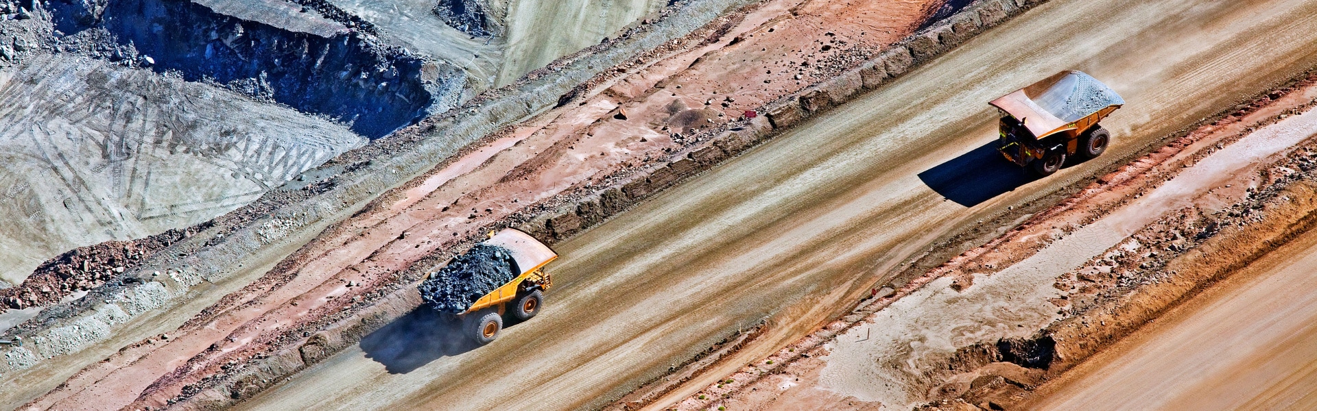 Vehicles carrying coal traversing an open cast mine