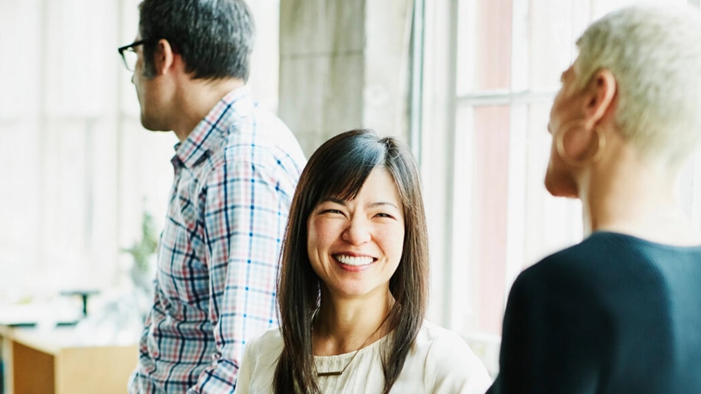 A picture of three people, of which one is turned towards the camera, smiling.