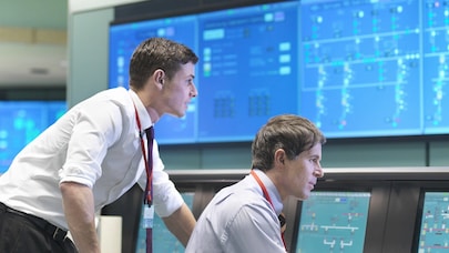 A picture of two people working at the same computer screen.