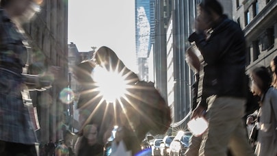 A blurry image of people walking in the city center with the sun in the background.