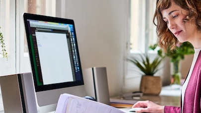 A picture of a woman working in a bright home office.