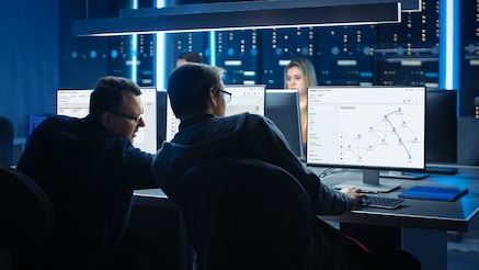 Two men looking at multiple monitors