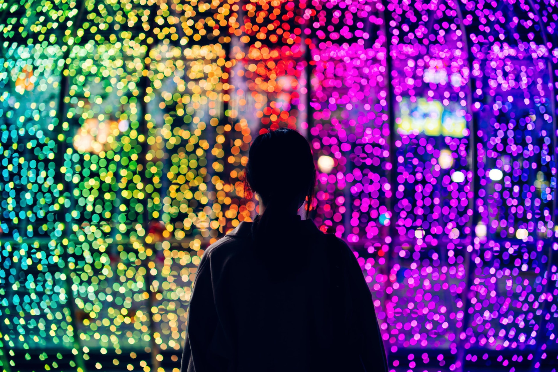 A person's silhouette against colourful lights.