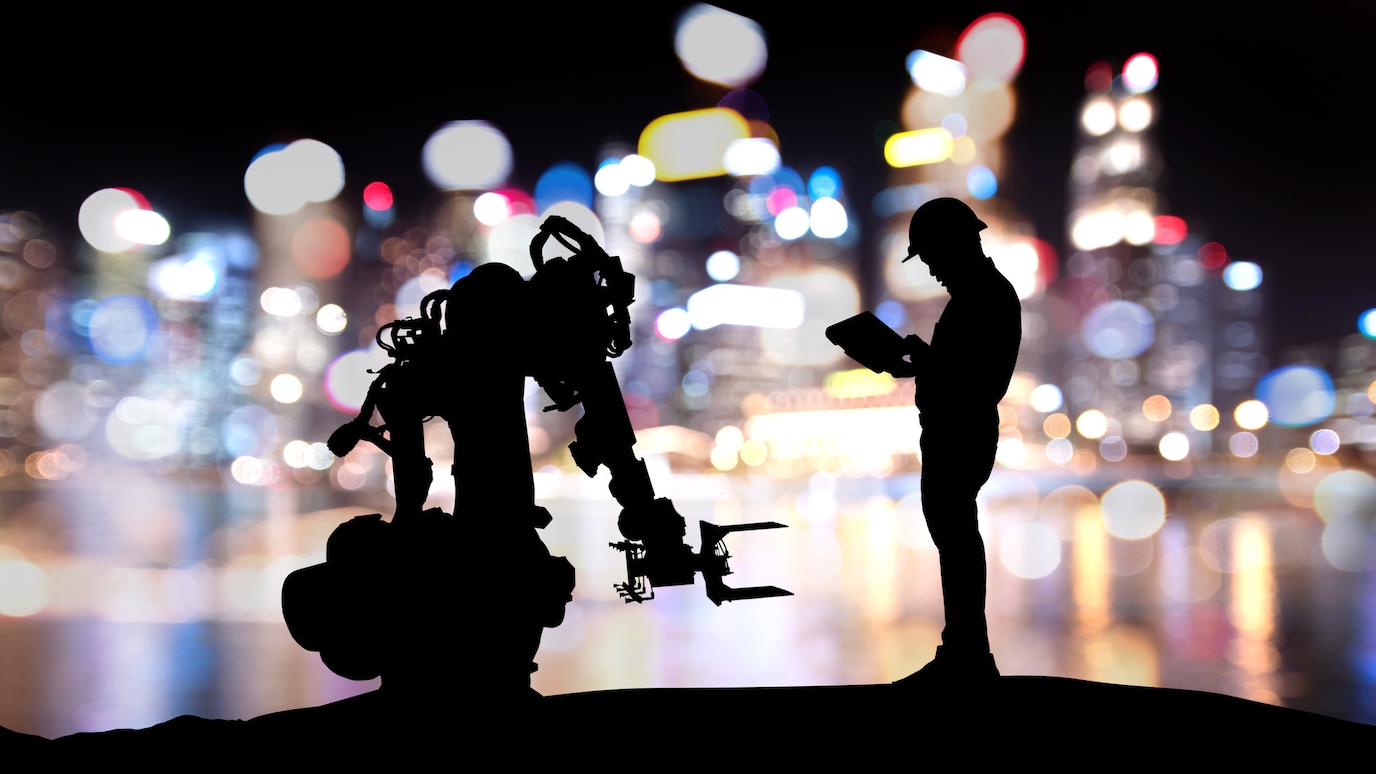 Silhouettes of a human and a robot with colourful lights in the background.