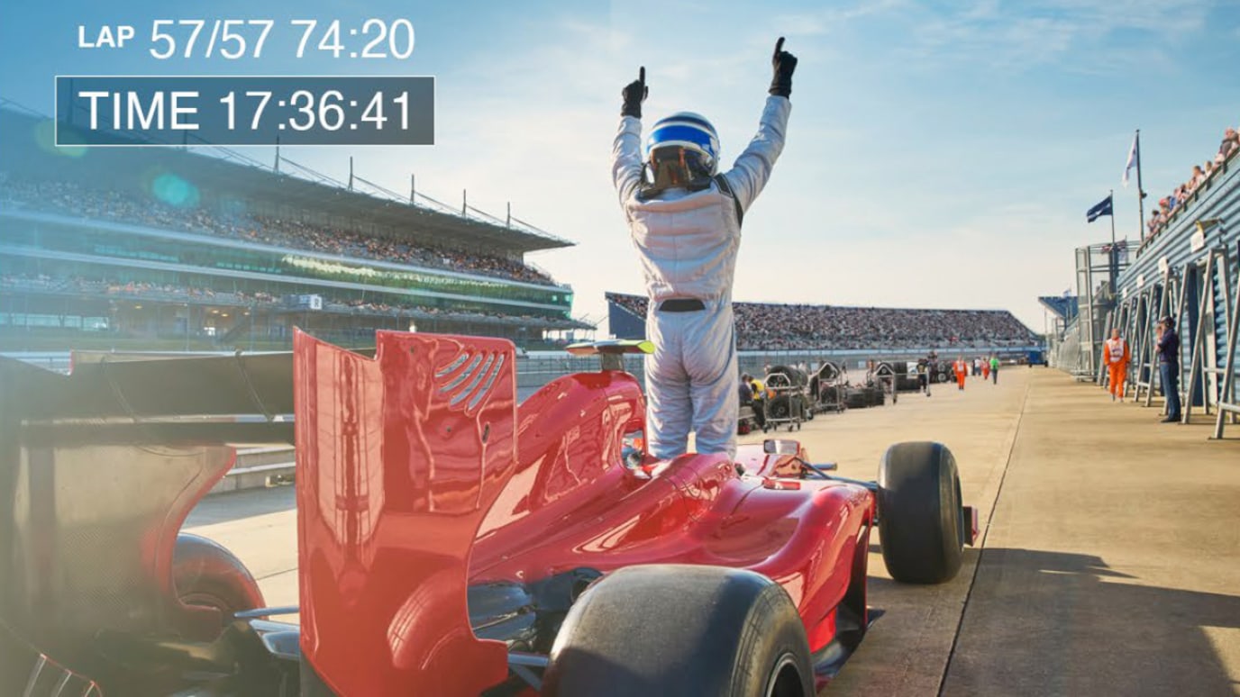 Formula One driver stands in front of red car in pit