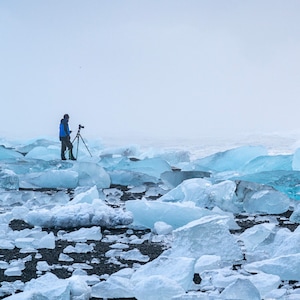 Photographer stands behind tripod on ice floe