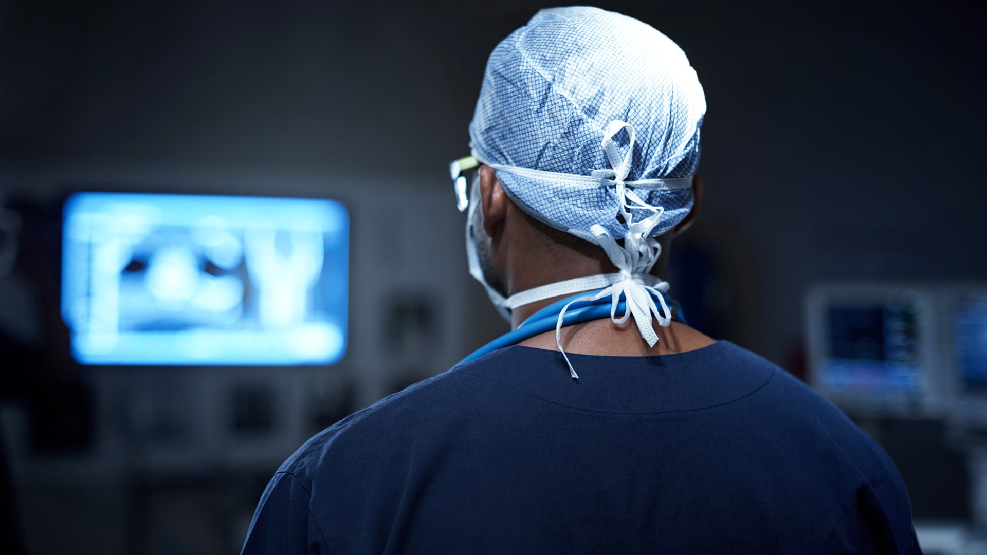 Doctor looking at monitor in darkened room