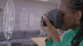 Woman looking through digital camera viewfinder with focus overlay graphic protruding from lens