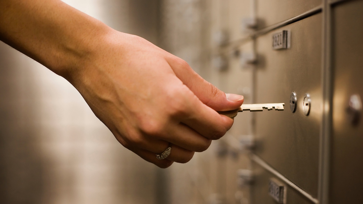 Hand with key in secure locker