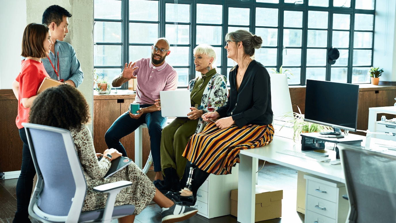 Work colleagues sitting around a desk in an open office