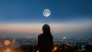 Silhouette of a person looking at the moon in the background 