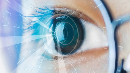 A close up of a person wearing glasses, reflecting a digital display