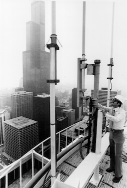 Bell Labs engineer Joe Nevarez inspects mobile telephone cellular system antennas in a roof top antenna platform in Chicago (1977).