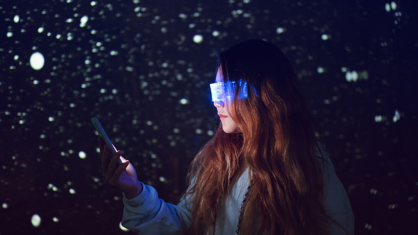 Woman wearing smart glasses looking at mobile device