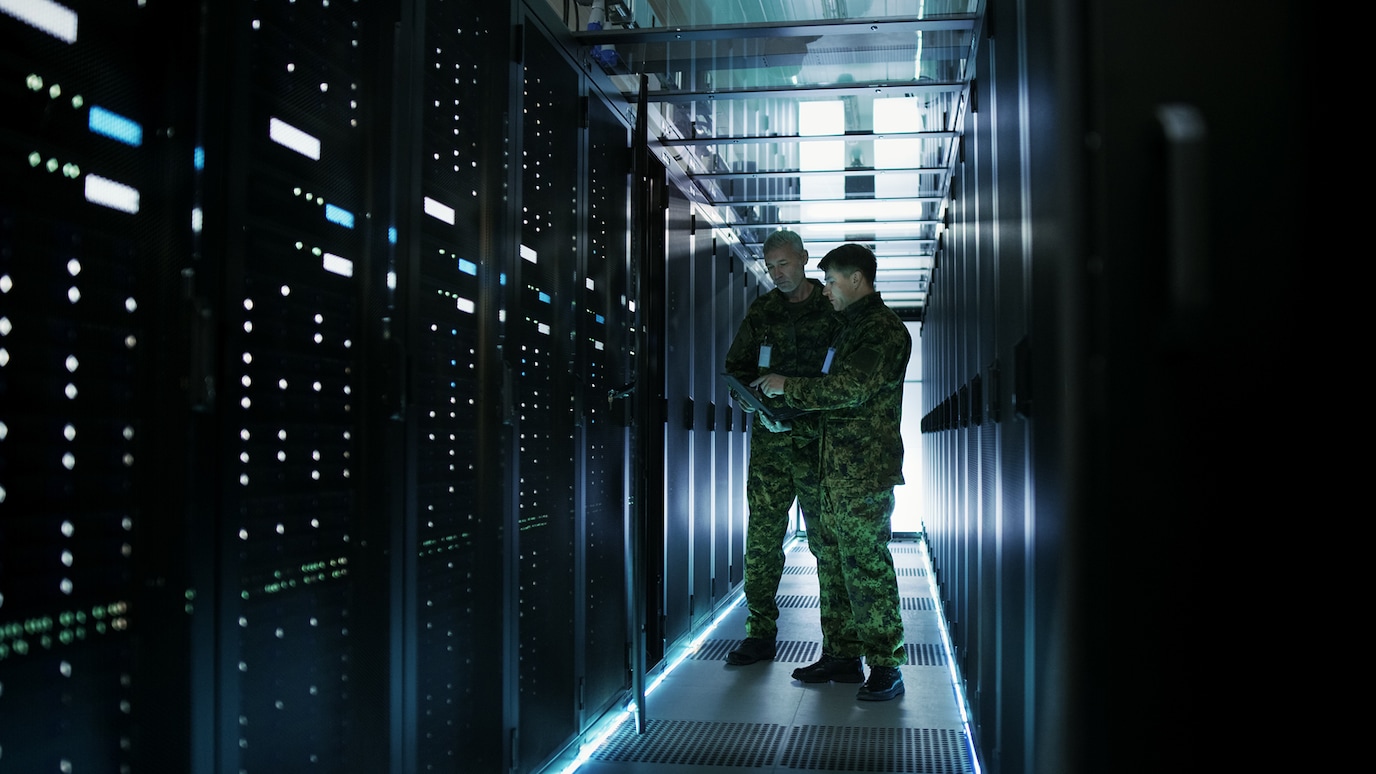 Two army personnel looking at tablet device in a data center