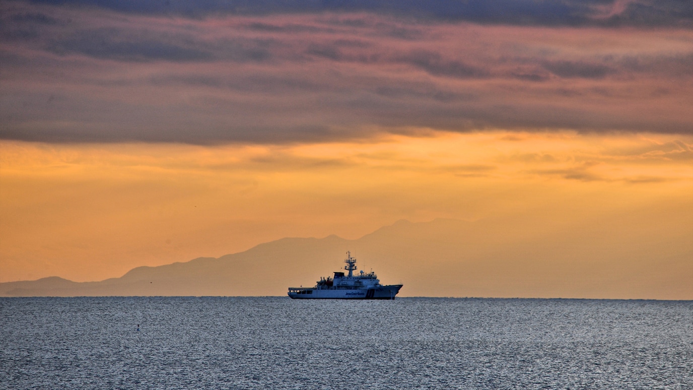 Vessel on sea at sunset