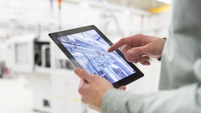 Person holding tablet device in an industrial setting