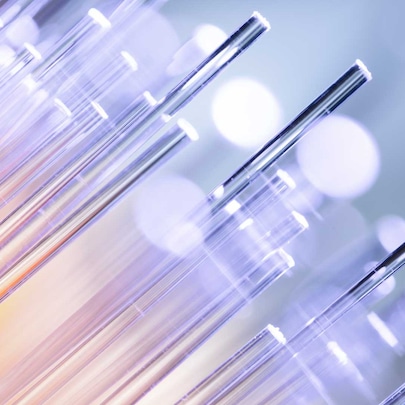 Close-up of glowing fiber optic cables with purple and orange hues against a blurred background with bokeh effect.