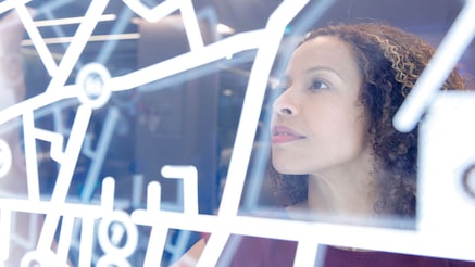 Profile view of a person gazing upward thoughtfully through a geometric pattern of white lines or framework.