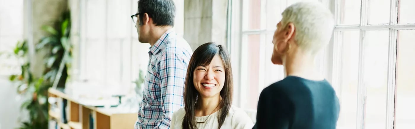 A picture of three people, of which one is turned towards the camera, smiling.