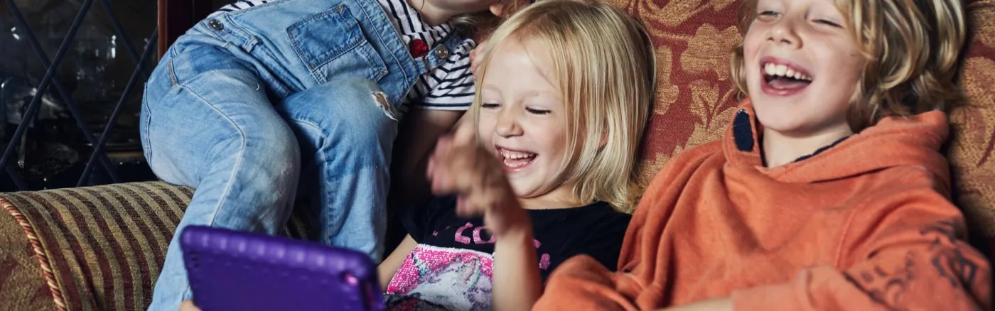 Laughing children on sofa looking at tablet