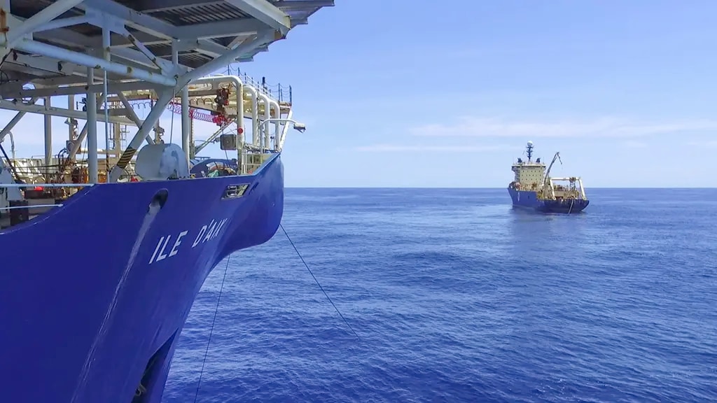 Two ships on a calm blue sea under a clear sky.