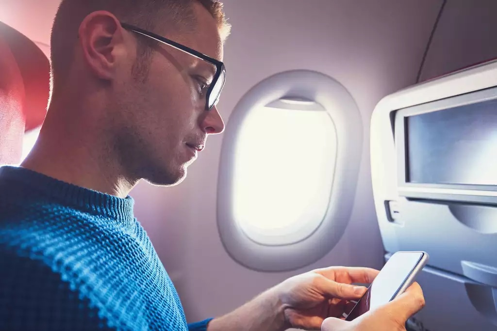 person checking phone on airplane