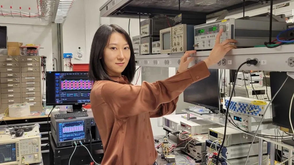 Qian Hu pressing a button on a piece of lab equipment