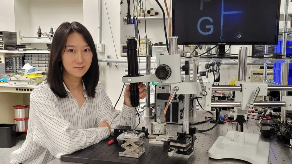 Qian Hu using a microscope