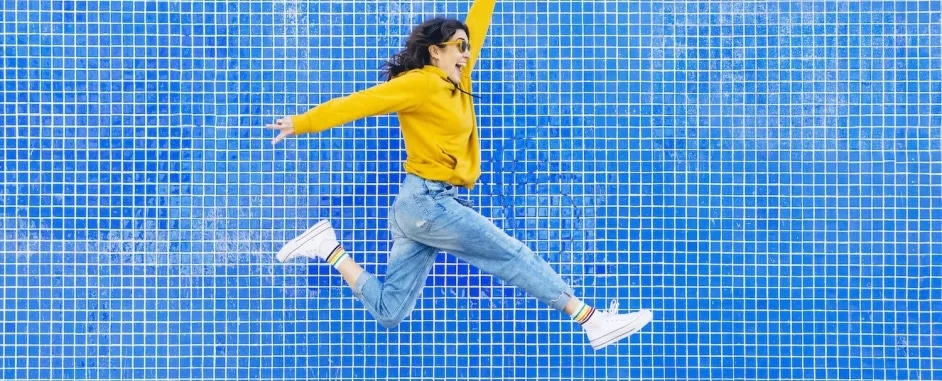 A woman jumping in front of a blue wall