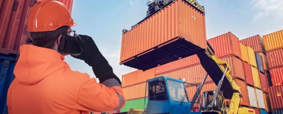 Containers are loaded by a forklift supervised by a worker