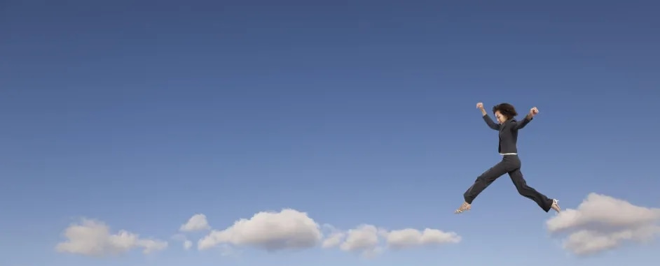 Businesswoman in suit walking on clouds