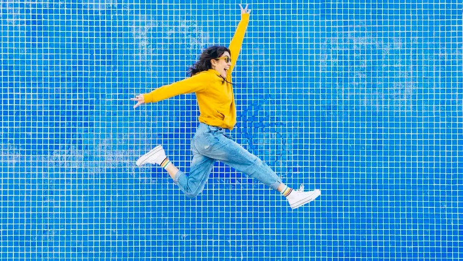 A woman jumping in front of a blue wall