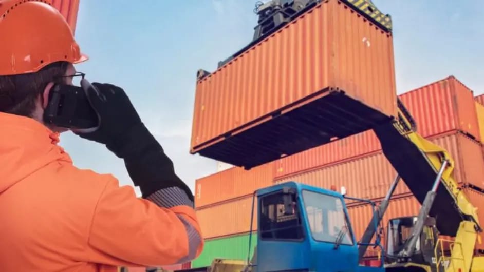 Containers are loaded by a forklift supervised by a worker