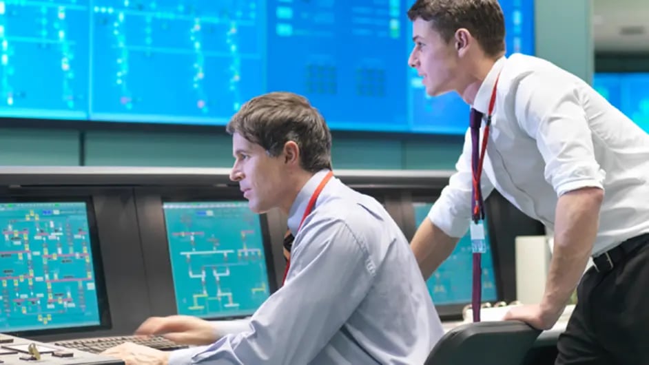 Side view of two people in a control room 