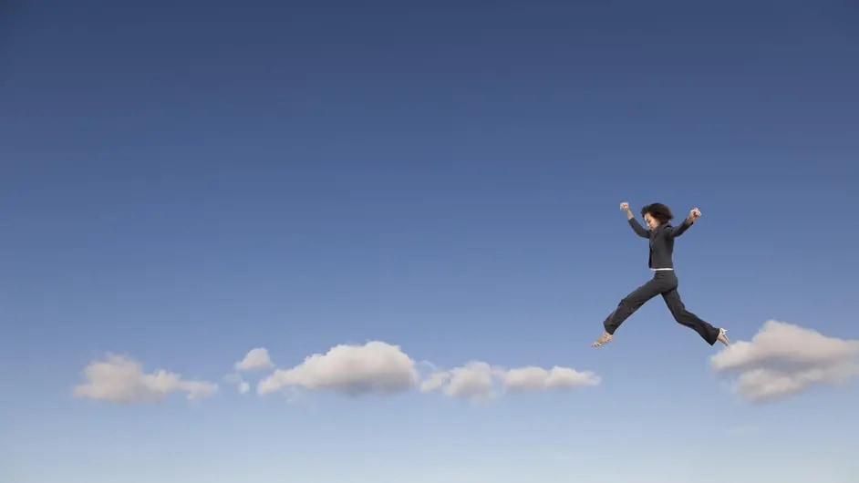 Businesswoman in suit walking on clouds