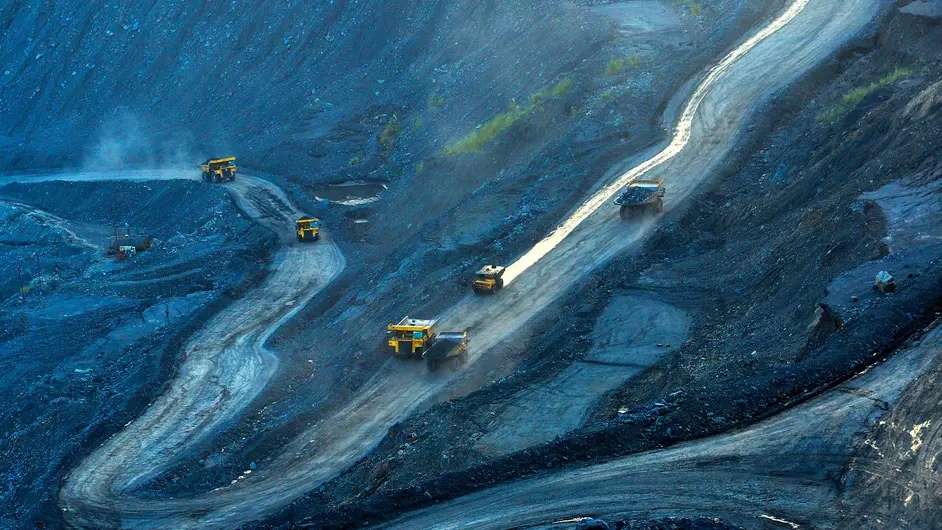 Yellow trucks traversing winding road in open cast mine