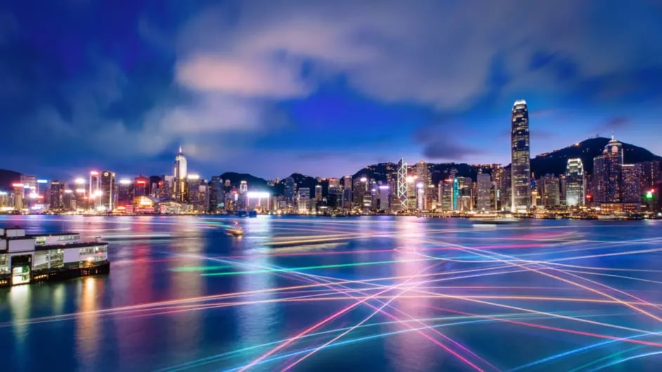 A night time view of a city skyline with colorful light trails in the water